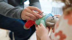 A person puts a stethoscope on a stuffed toy