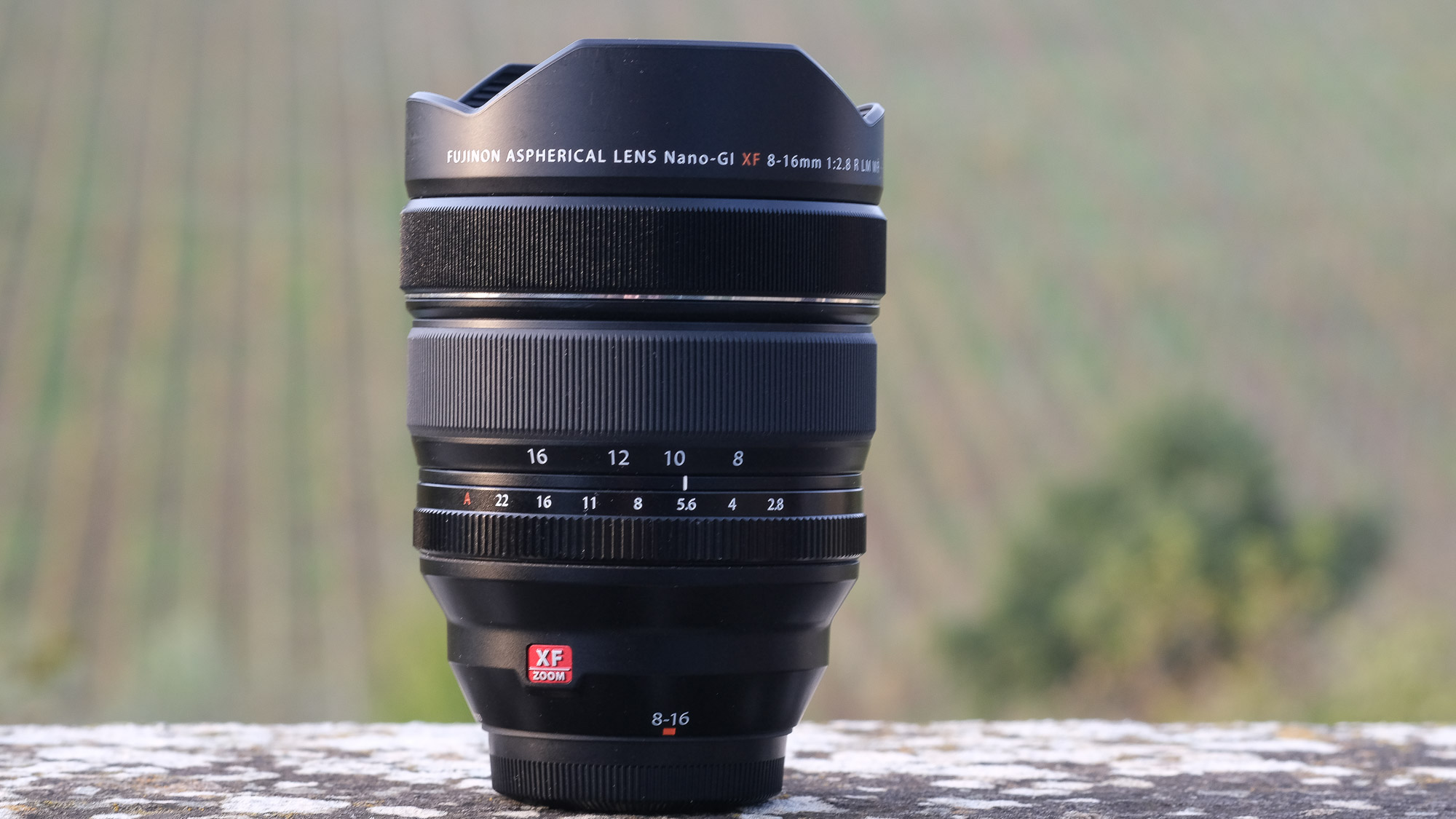 Photograph of Fujifilm XF 8-16mm standing vertical on stone surface