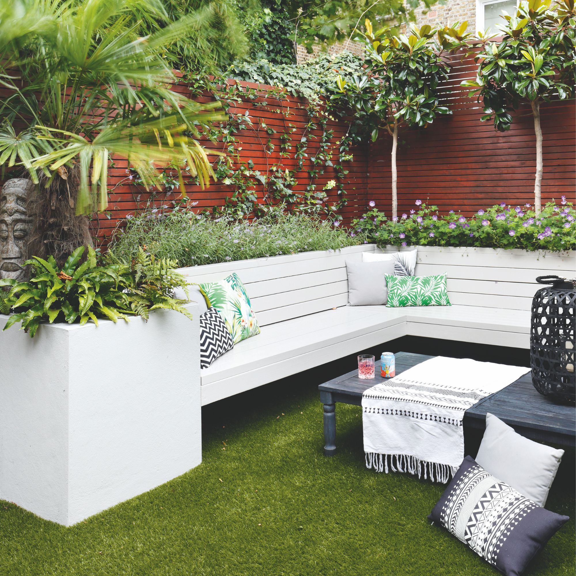 garden seating area with wooden benches and plants around the back of them