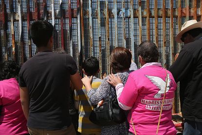 DREAMERs and their parents pray at a Mexican border fence.