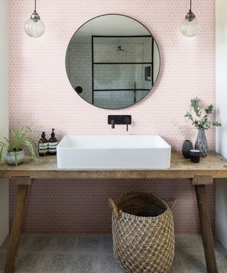A bathroom with pink penny mosaic tiles, a mirror, and a sink