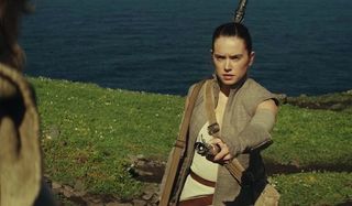 Rey handing lightsaber to Luke Skywalker