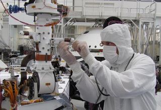 In this image, the technician's hands are just below one of the two REMS (Remote Environmental Monitoring Station) booms. The other boom extends to the left a little farther up the mast. This photo was taken during installation of the REMS instrument in September 2011, inside a clean room at NASA’s Jet Propulsion Laboratory in Pasadena, Calif.