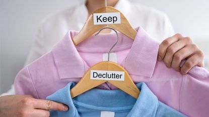 Woman holding two coat hangers with clothes and signs: declutter and keep