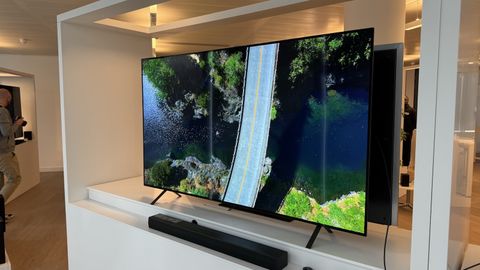 The LG B4 photographed on a white shelf in a showroom. On the screen is an aerial shot of bridge across water