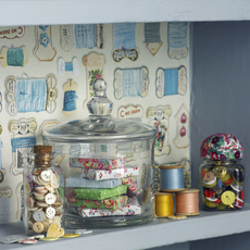 craft room with bespoke shelving wall behind with wallpaper and jars and baskets kit on the shelves