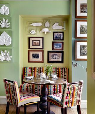 Green dining nook with bench seating, wooden table, chairs, artwork on wall