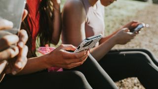 Three woman holding their mobile phones outside and looking at the screens - stock photo