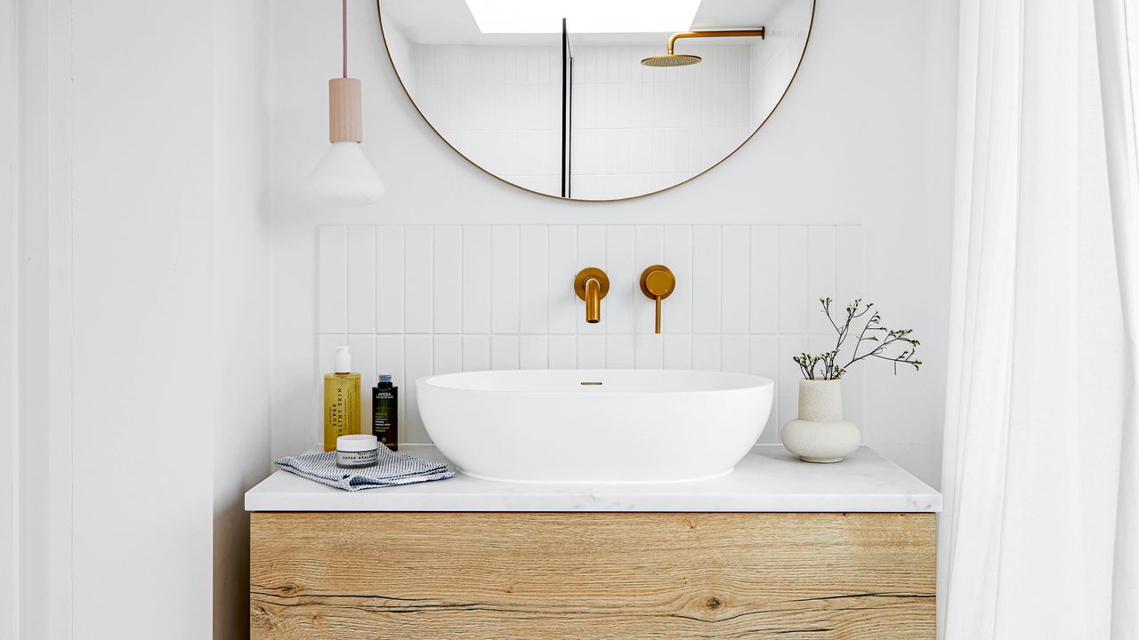 Bathroom with white walls, wooden washstand and round mirror