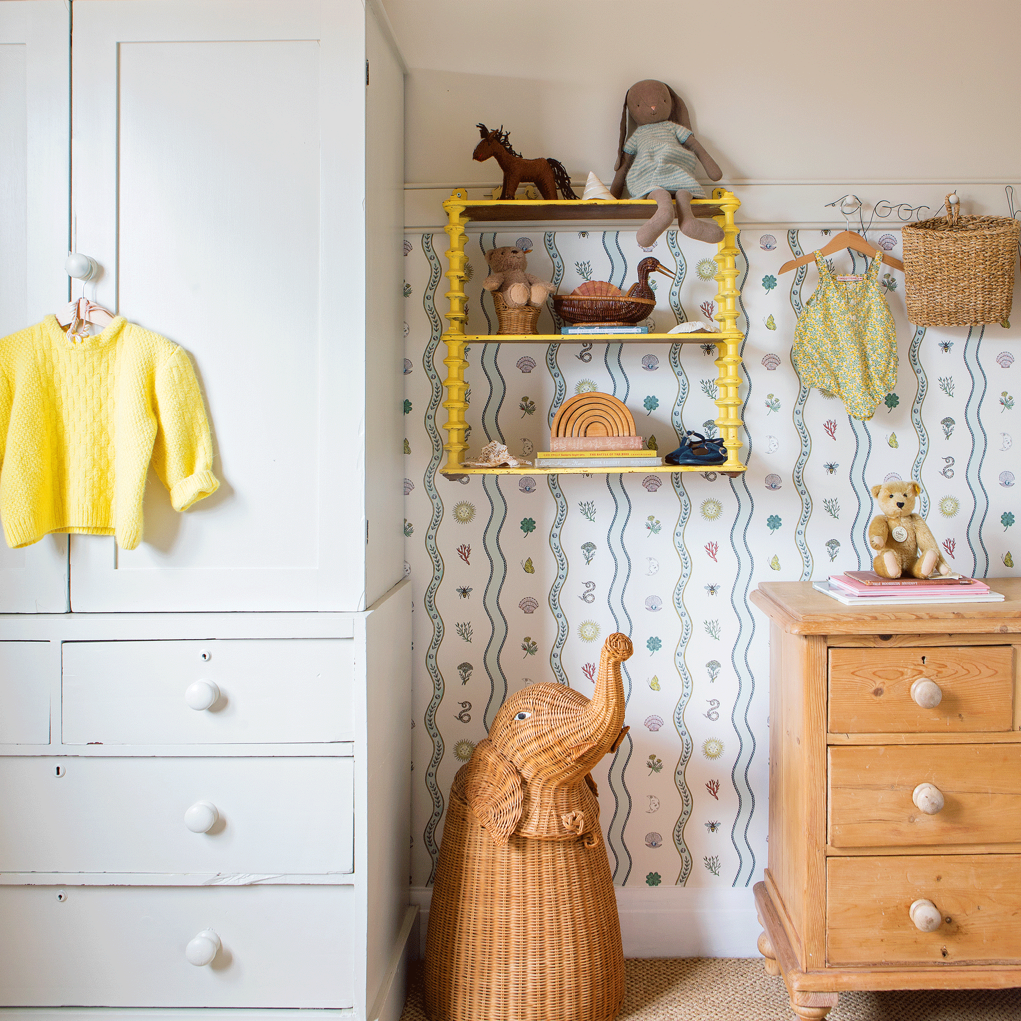 a child's bedroom with wardrobe, and chest of drawers, an elephant-shaped basket and a yellow wall-hung shelving unit