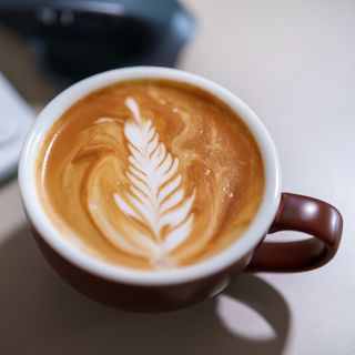 Latte art in dark mug on table top