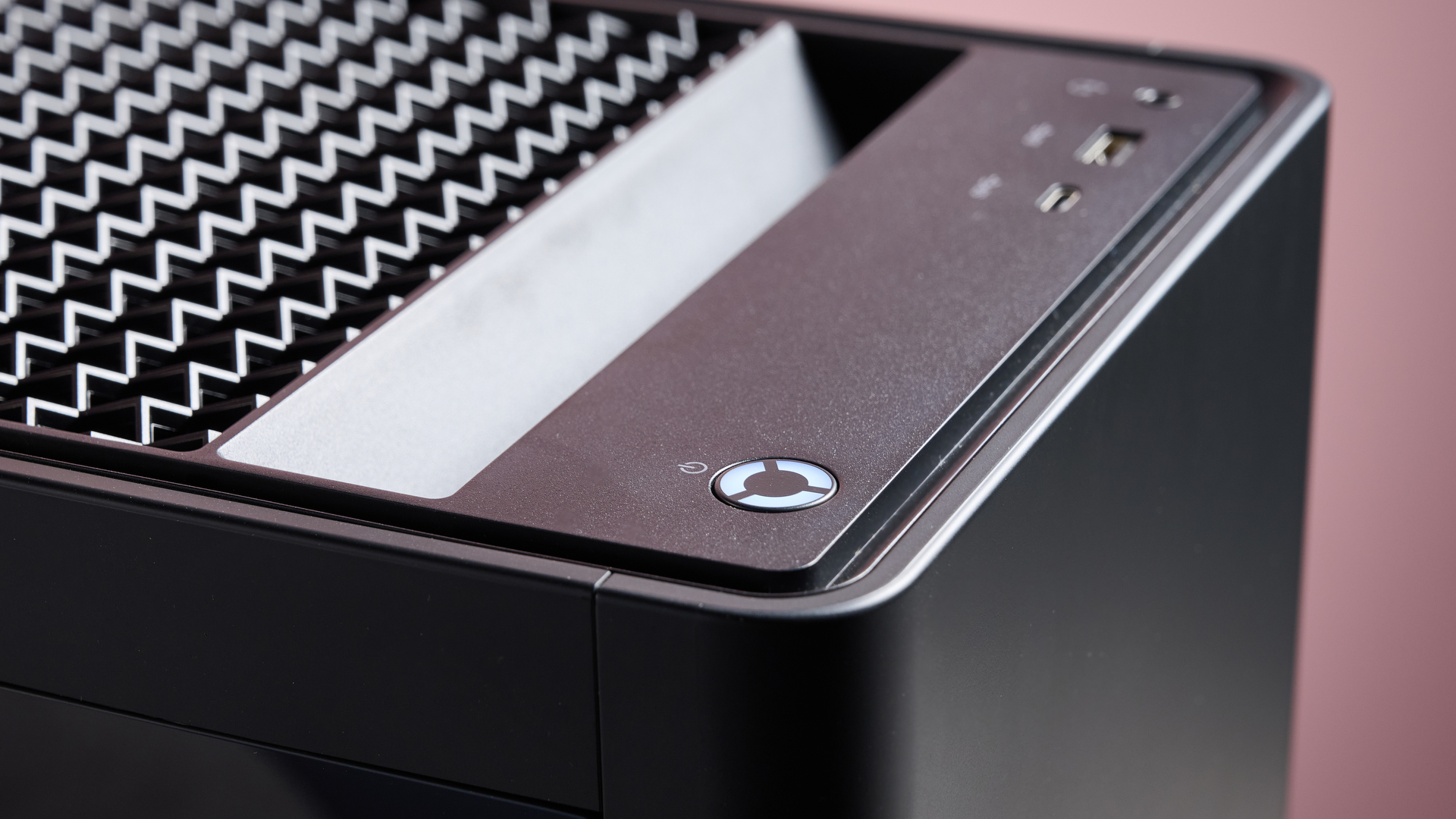 Close-up of power button and grab handle on the Lenovo Legion Tower 5, with pink wall in background