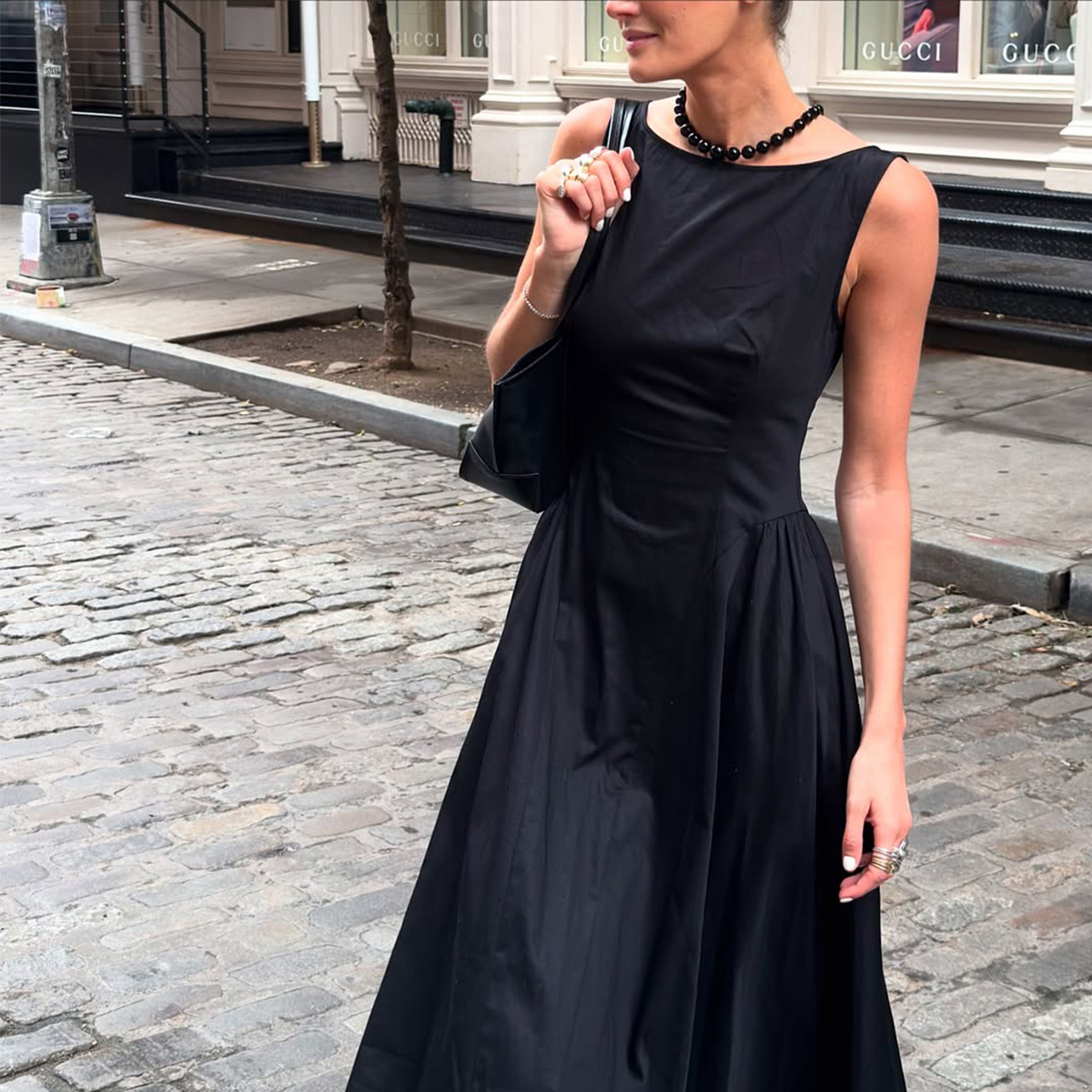 Coco Schiffer wearing a black dress, necklace, and bag.