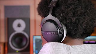 Beyerdynamic DT 770 Pro X Limited edition worn by a man, facing away from the camera, with bookshelf speakers in the background