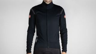A male model in a black cycling jacket with castelli logos in red on both upper sleeves