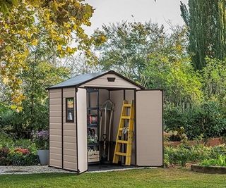 Grey shed with tools in a green garden