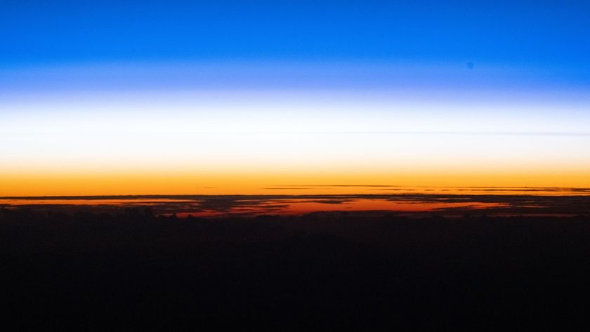A sunset showing the black curve of the Earth with a golden band of light just above and a blue band of light above that