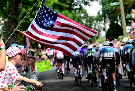 A fan holds a US flag as the peloton passes during the 2026 Philadelphia Cycling Classic