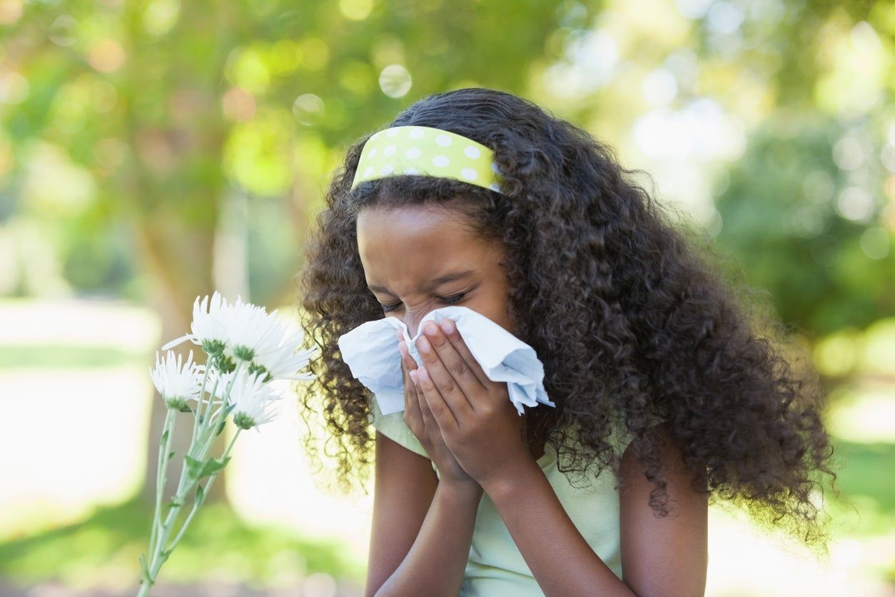 Child Sneezing Next To White Flowers