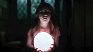 A girl holds a light in a dark room