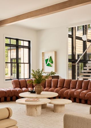 A living room with a leather couch and a trio of marble coffee tables