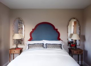 A bedroom with two mirrors behind the bed