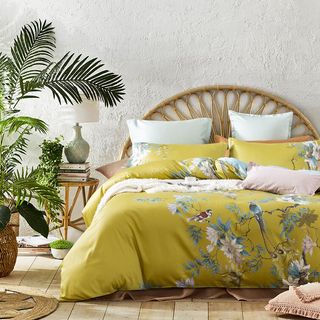 bedroom with citrus yellow botanical bedding and rattan headboard