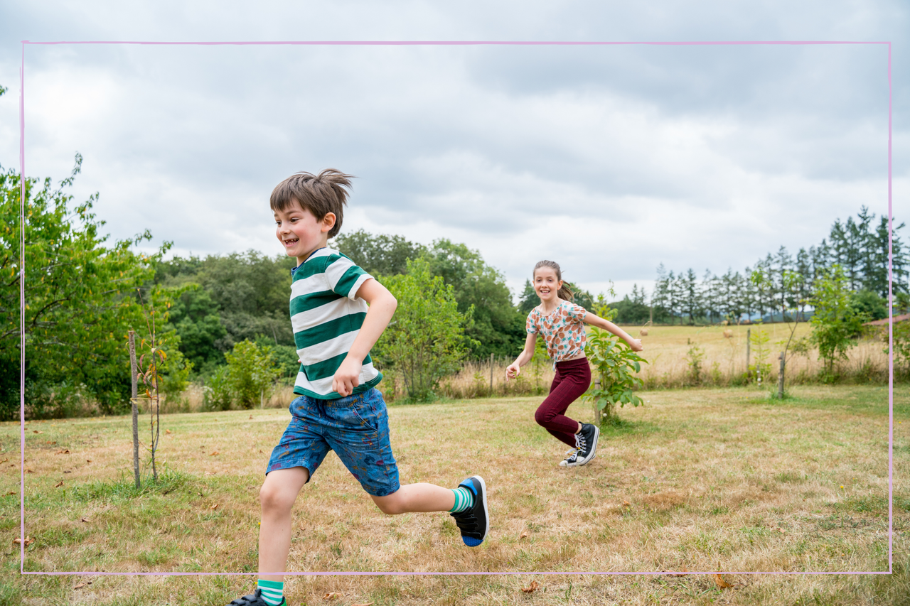 Full length view of blonde little girl and boy running on the garden in holidays