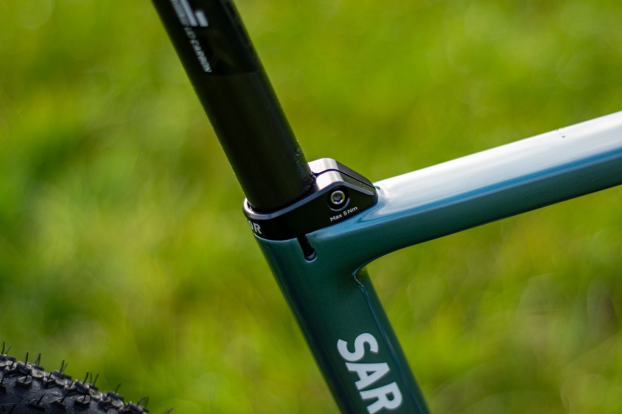 A blue Factor Sarana gravel bike in a grassy field with a hedge in the background