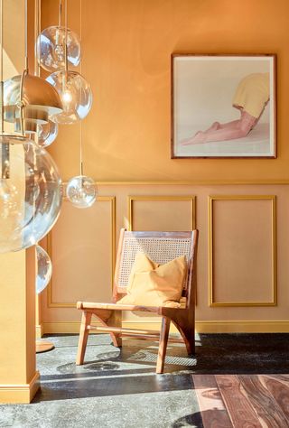 Lindley Lindenberg lounge with marble and wooden flooring, wood and rattan chair and yellow walls