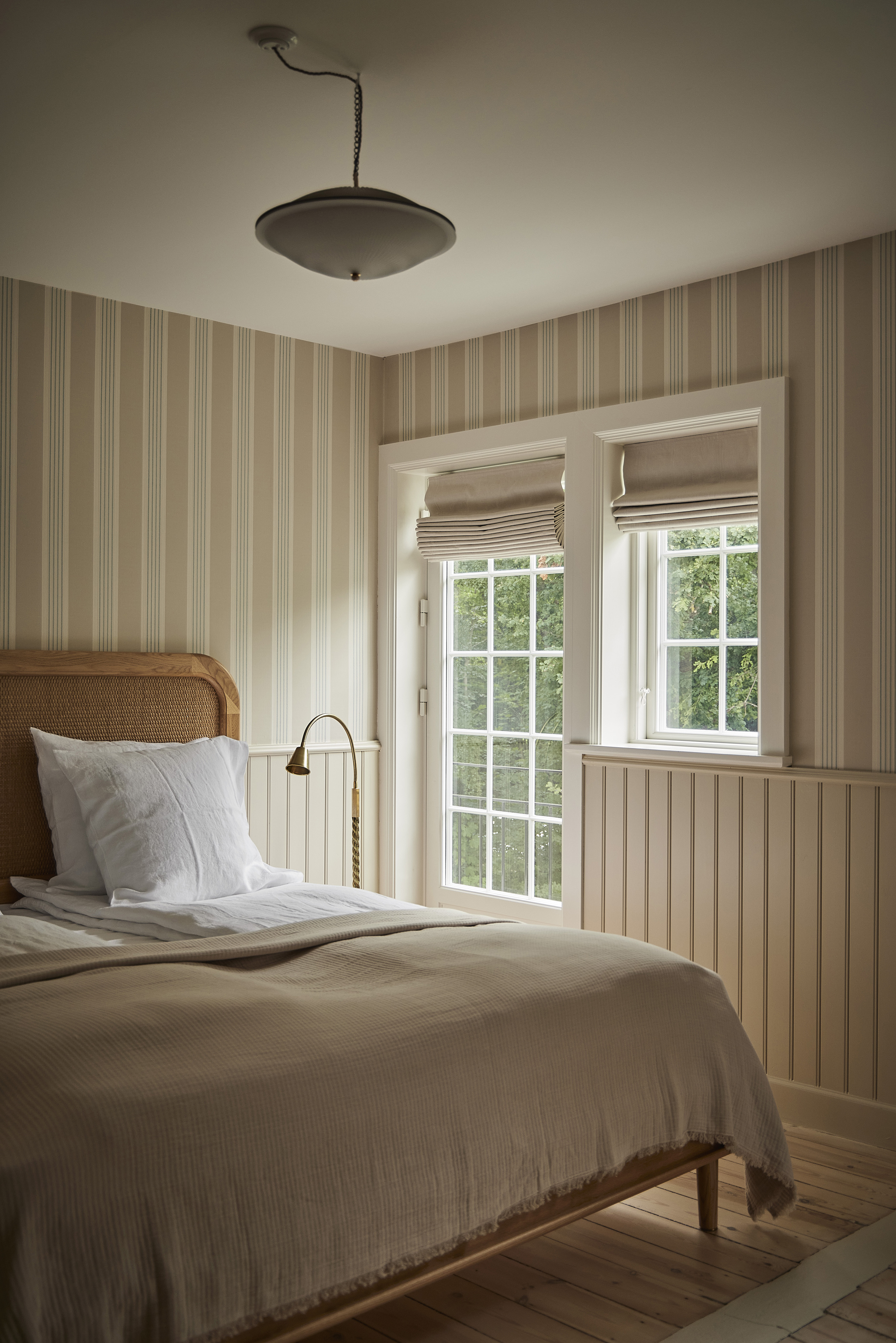 a bed in a bedroom with striped wallpaper in neutral colors