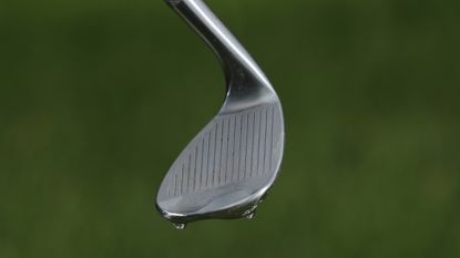 A golf wedge covered in water 