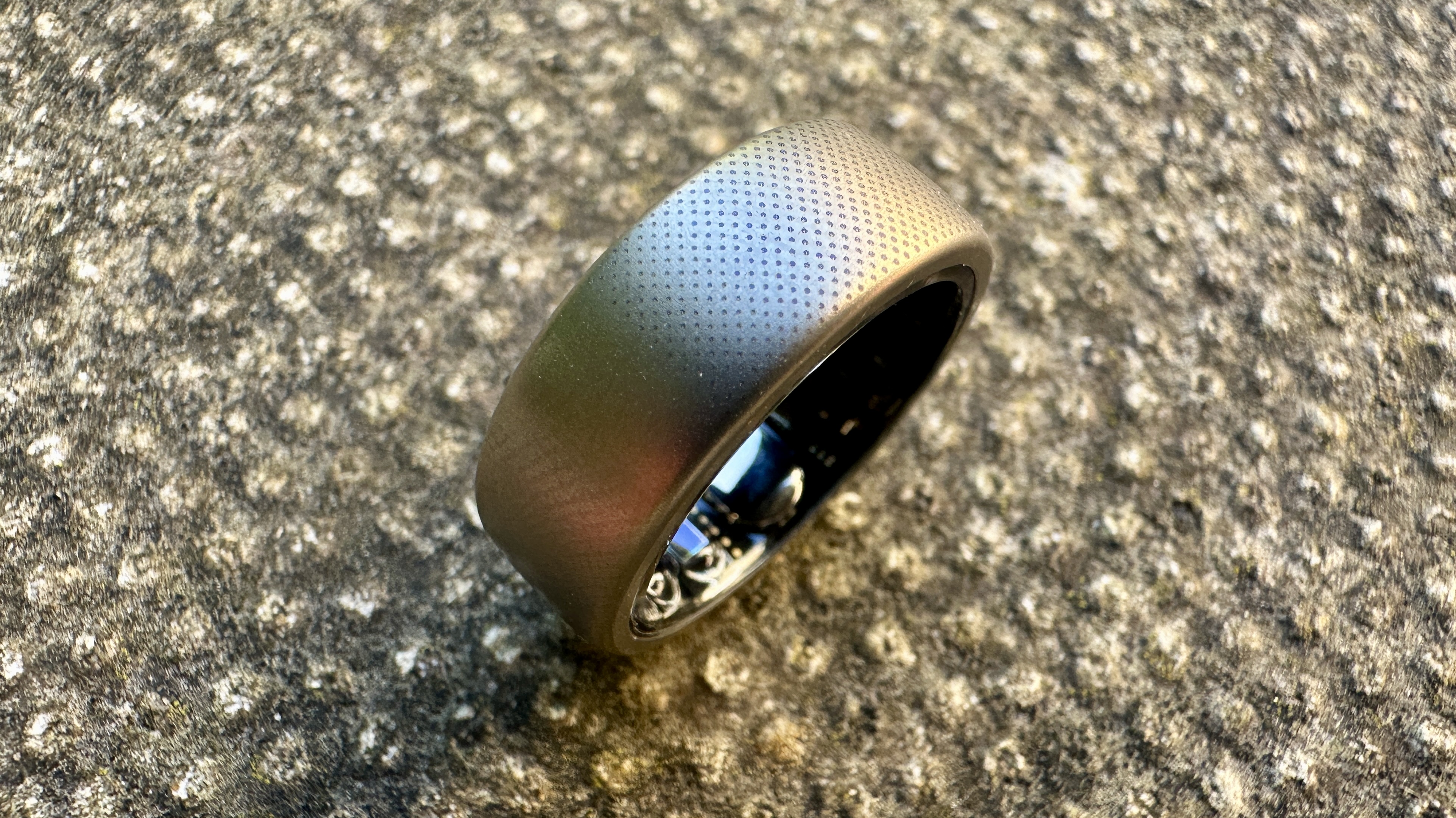 A close-up of the texture of the Amazfit Helio smart ring against a concrete background.