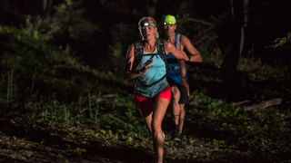 Man and woman running in forest at night - tips for trail running at night