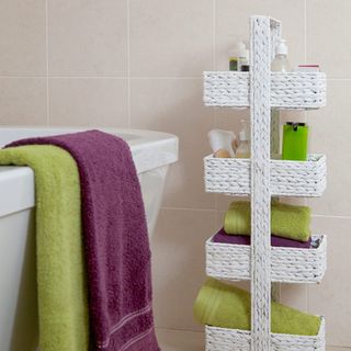 bathroom with white narrow storage unit and towels