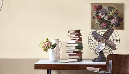 Old fashioned fan sat on a desk, surrounded by books and artwork