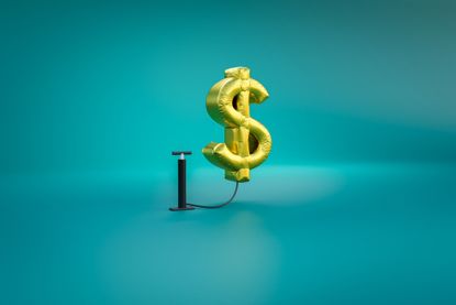 gold dollar-sign balloon being inflated by a bike tire pump with a teal background