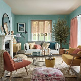 bleu living room with grey sofa and large round mirror on mantle above fireplace