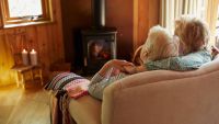 Elderly couple sitting next to a wood burning stove