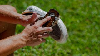 A person cleaning a pair of running shoes with a brush