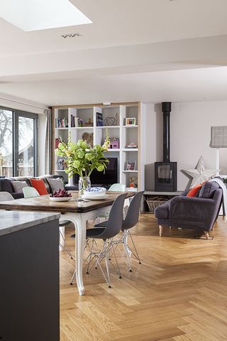 open plan dining and living areas with open shelving, a stove and wooden parquet flooring