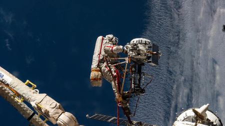 Cosmonaut Sergey Ryzhikov is seen at the end of the European robotic arm as he works on a high‑resolution camera during a 6-hour spacewalk outside the International Space Station on Oct. 16, 2025.