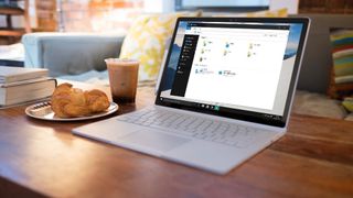 Laptop on desk with coffee and books beside it 