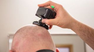A man uses an electric head shaver to shave his bald head