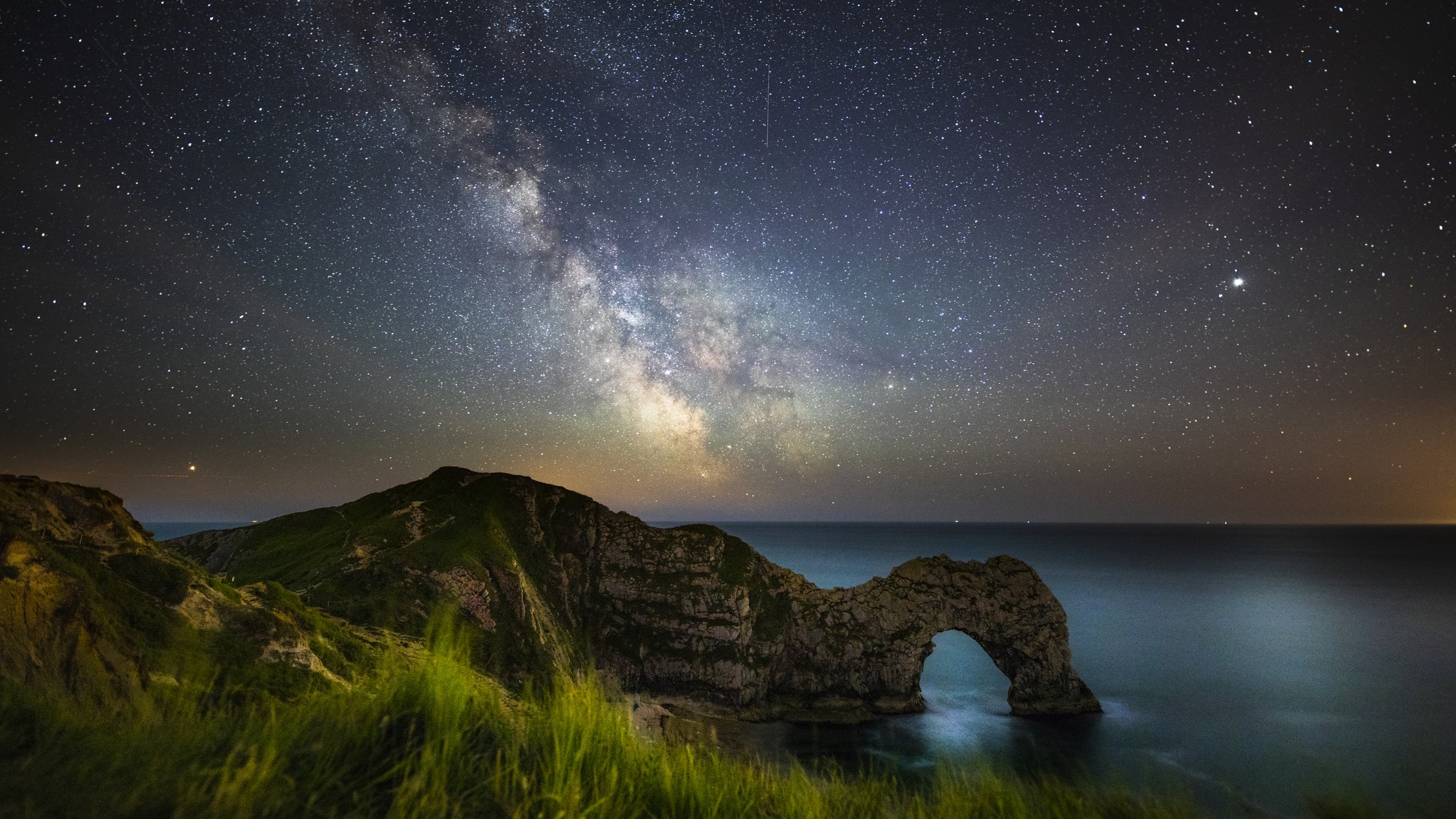 Night sky with milky way moving over the famous Durdle Door on the Jurassic Coastline of Dorset, UK