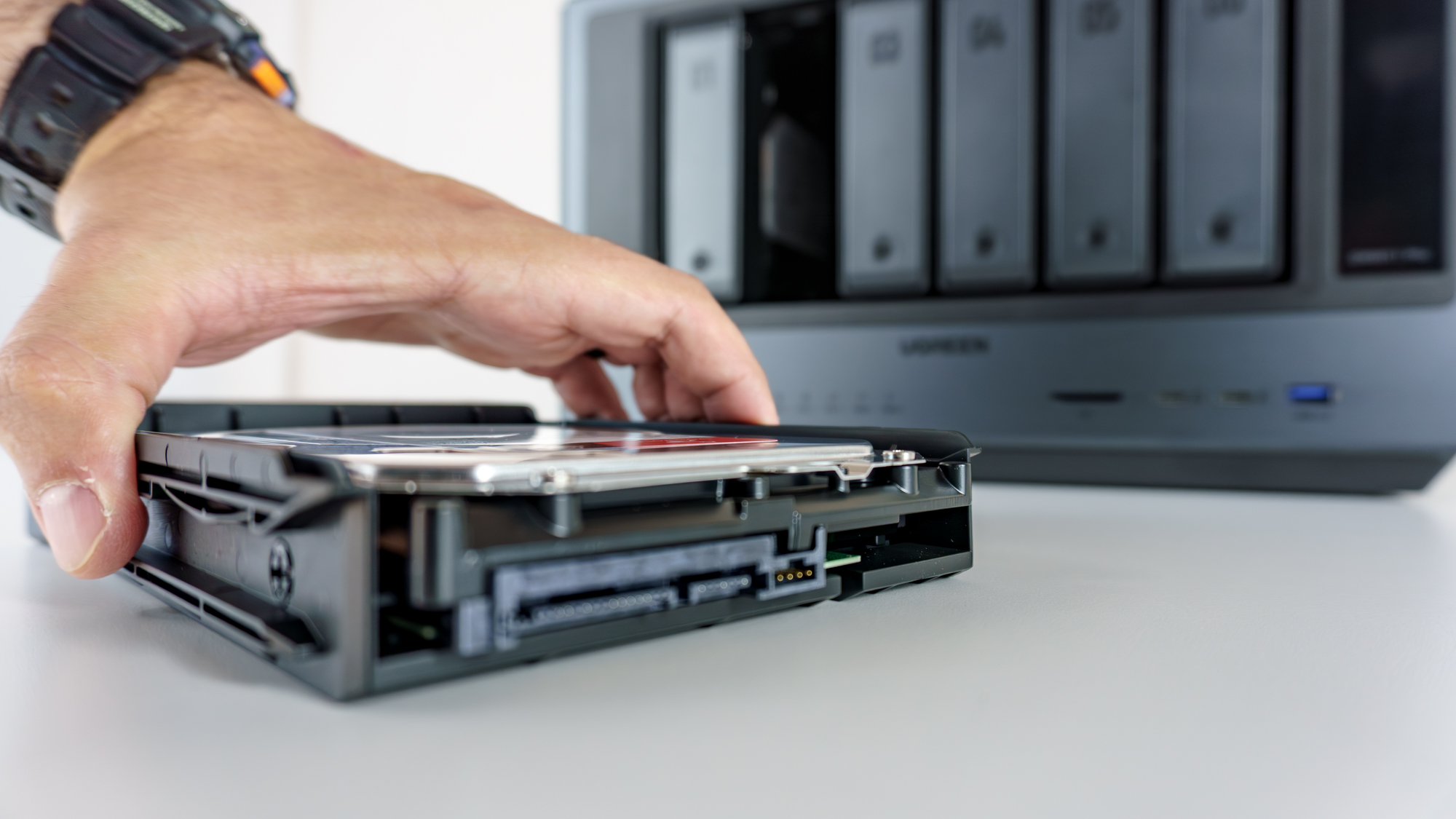 A person putting a hard drive into one of the Ugreen iDX6011 Pro's drive enclosures