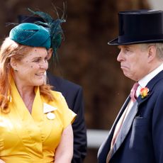 Sarah Ferguson in a yellow dress smiling at Andrew, who is scowling in a top hat