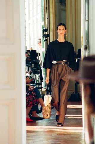 a model walks at The Row's latest runway show in oversize trousers a black t shirt and slides