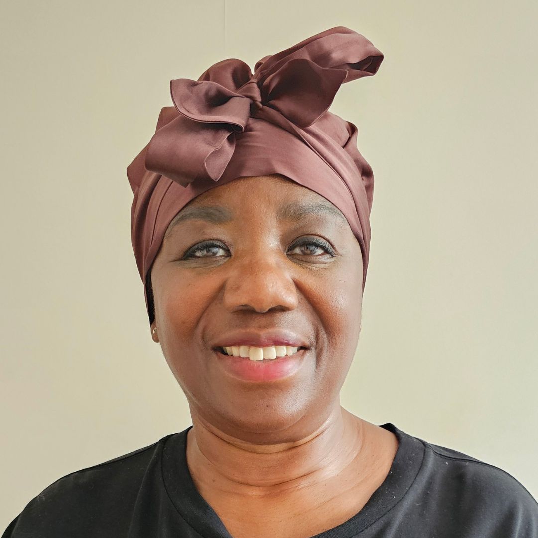 Joyce Connor pictured wearing the Lilysilk Multiuse Silk Tie Bonnet silk hair wrap, tied around her hair and smiling to the camera