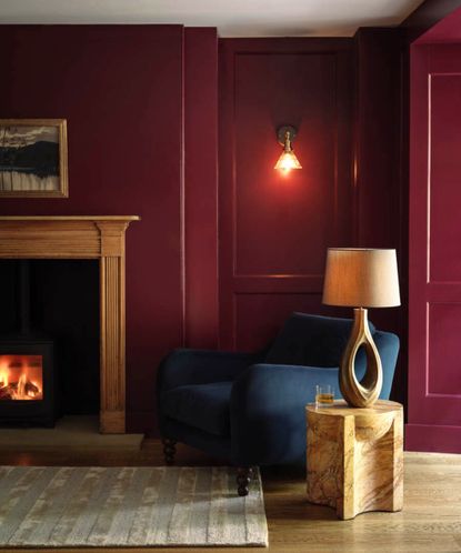 Burgundy room with a a fireplace, navy blue chair and lighting by Industville